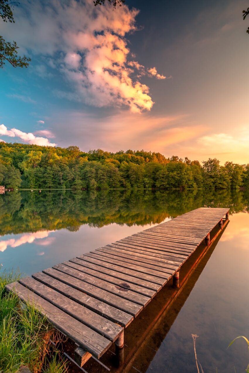 serene lake with wooden pier at sunset