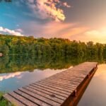 serene lake with wooden pier at sunset